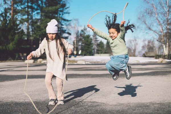 Två barn hoppar hopprep på Bollnästorget på Skansen
